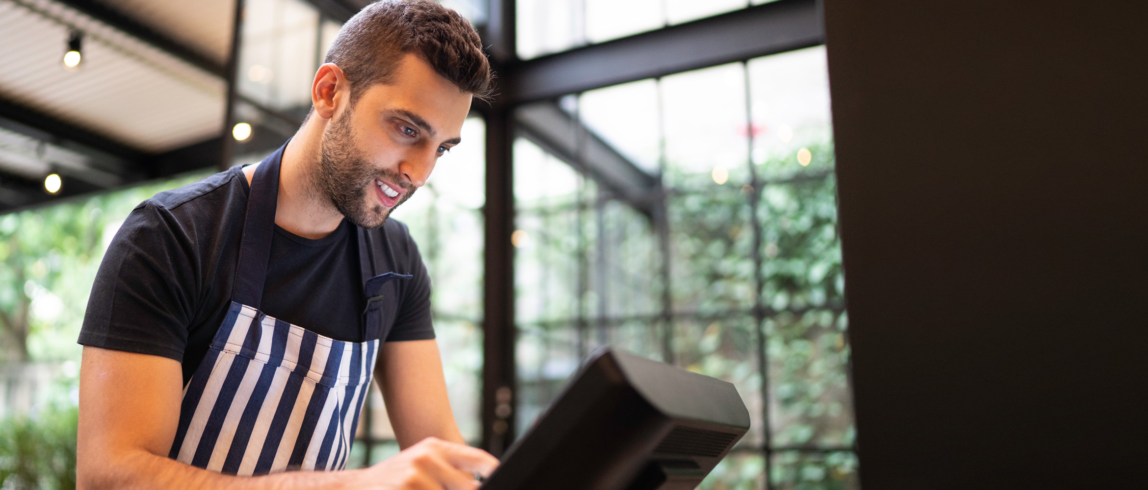 RestaurantMitarbeiter GIBT-Daten in Kasse ein, lächelnd