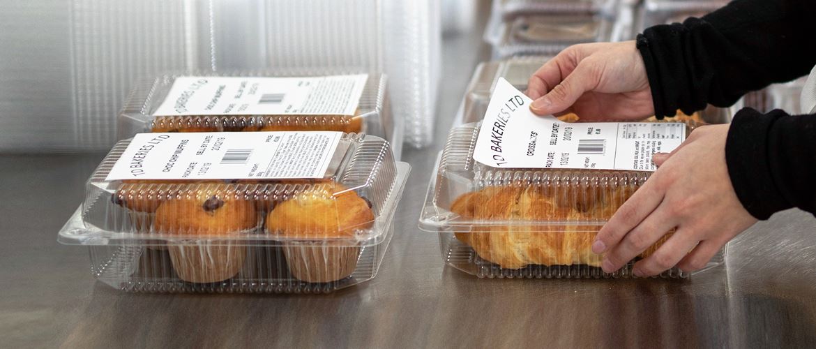 Hände Kleben Brother Etikett auf Lebensmittelverpackung, Muffins und Croissants