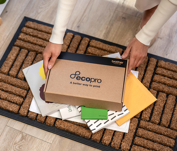 Person, die eine Ecopro-Box auf einem Stapel von Post auf der Fußmatte aufhebt