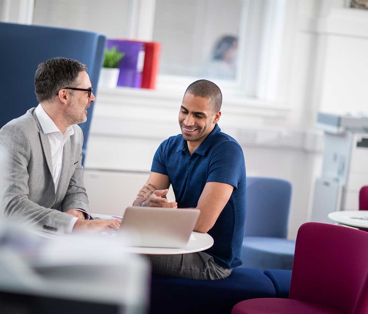 Two males sat at a computer in an office environment 