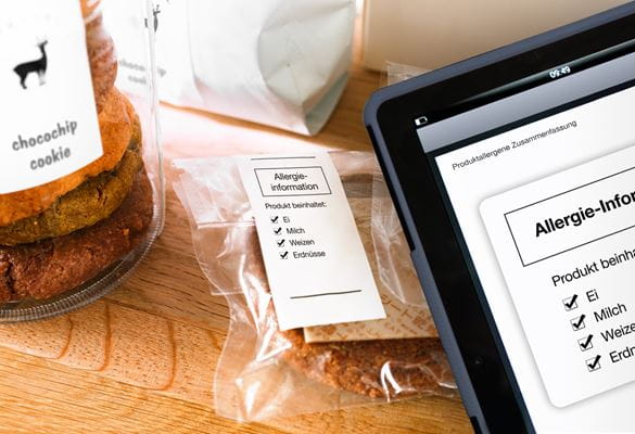 Tablet mit Menüverwaltungssoftware und Cookies mit Lebensmitteletiketten im Hintergrund