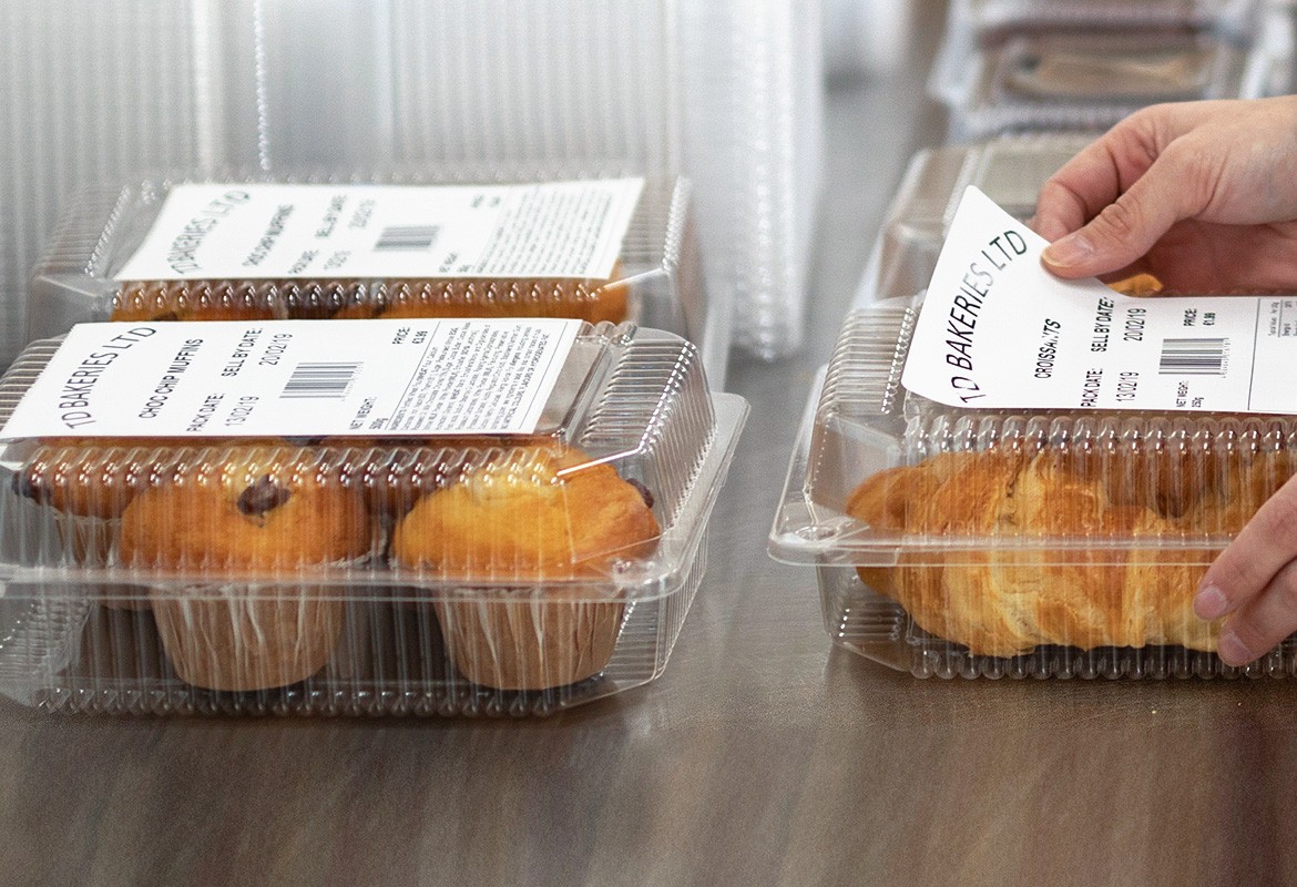 Hände Kleben Brother Lebensmitteletikett auf Vorverpackte Lebensmittel, Muffins und Croissants