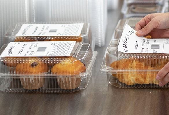 Hände kleben Brother Lebensmitteletikett auf vorverpackte Lebensmittel, Muffins und Croissants