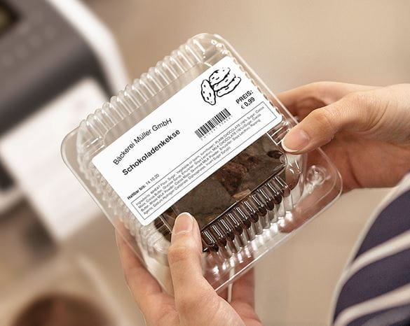 Eine Person hält eine Verpackung in der Hand auf das Lebensmitteletiketten geklebt sind