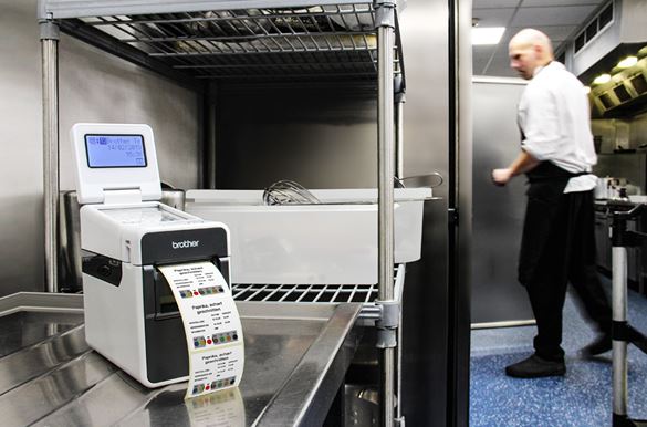 TD-Etikettendrucker druckt Warenrotationsetiketten in Restaurant-Küche, Koch im Hintergrund an Kühlschrank