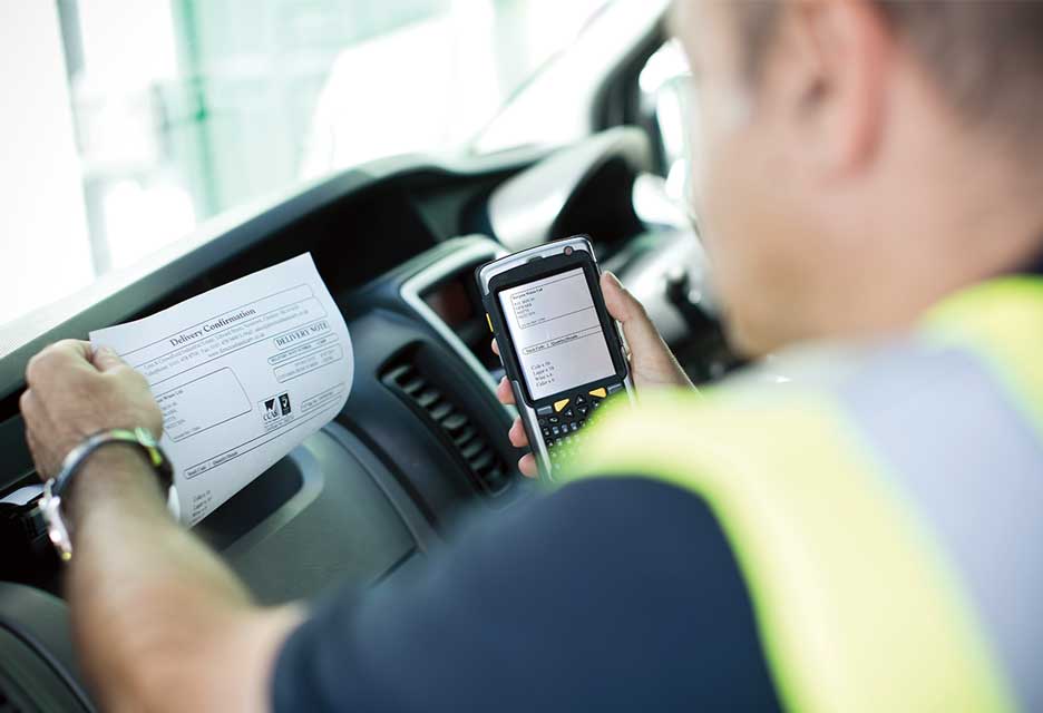 Mann mit Warnweste druckt ein Dokument in der Fahrerkabine AUS