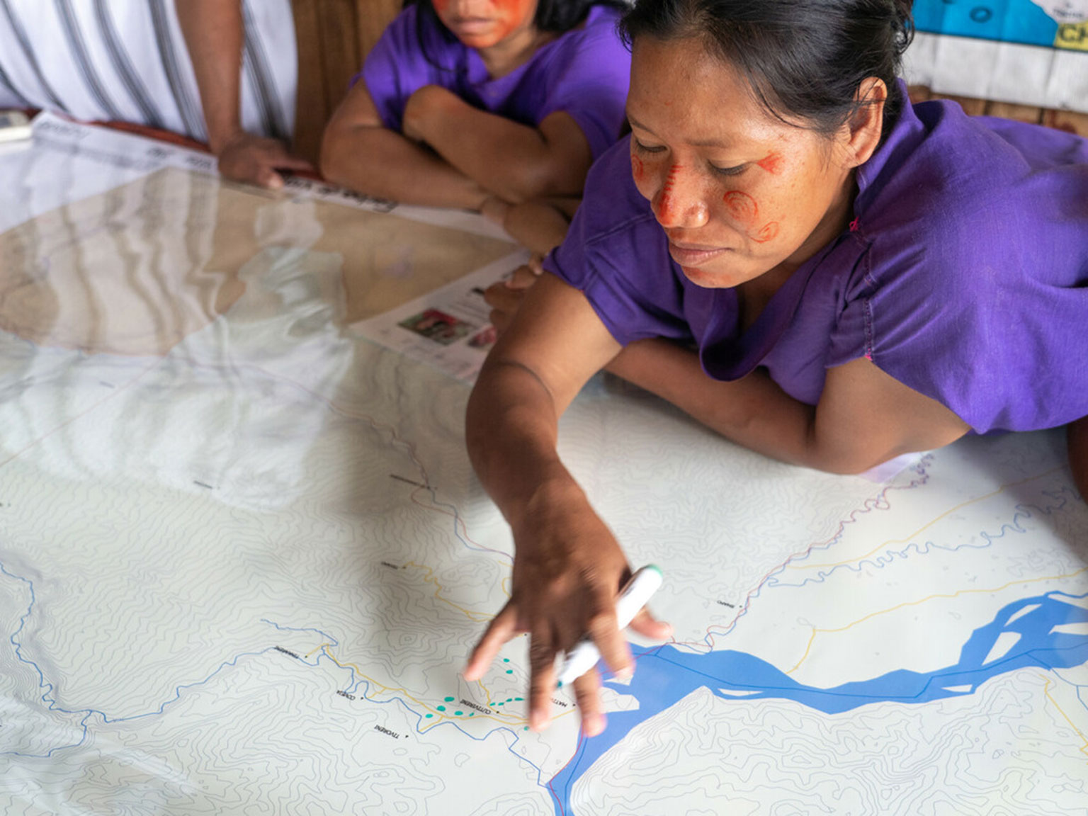 A woman looking and drawing on a map with others in the background