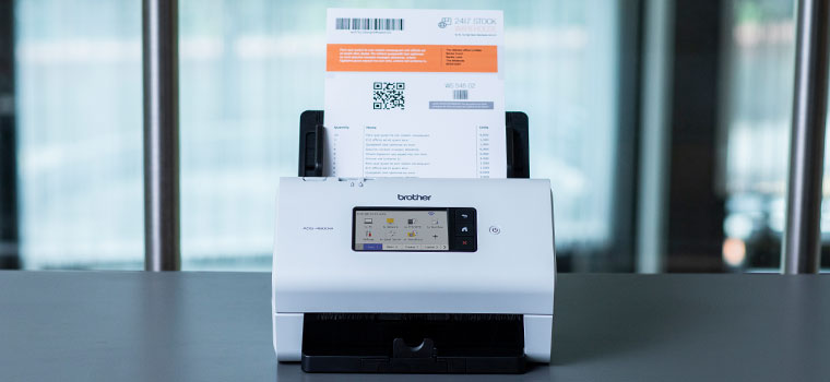 Brother ADS-3600W Desktop-Dokumentscanner auf dem Schreibtisch mit Notebooks
