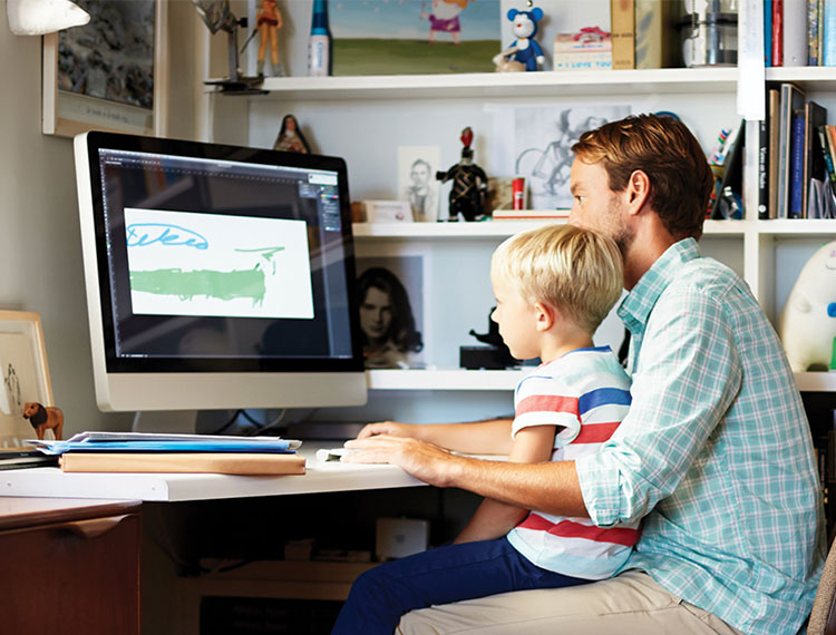 Vater mit Sohn vor Computer im Büro