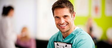 Lächelnder Arzt im Grünen Kittel mit Klemmbrett in der Hand