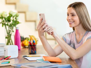 Frau zu Hause mit ihrem Smartphone zum Drucken zum P-Touch Cube-Label und zum Banddrucker