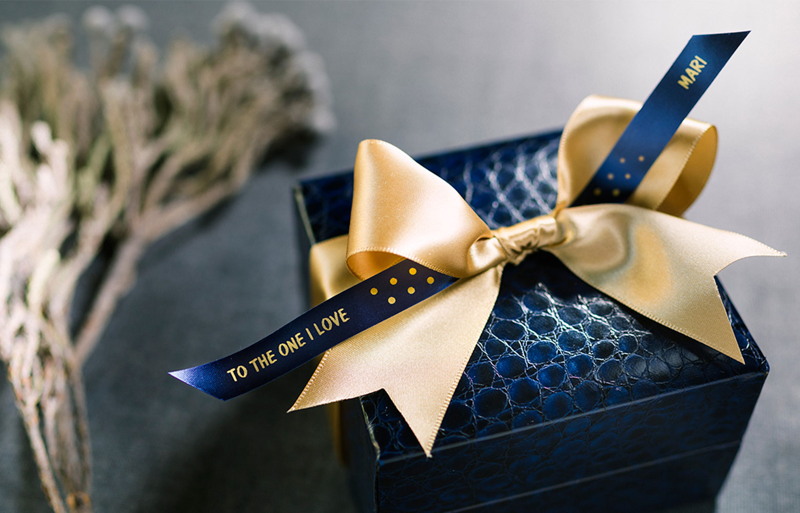 Schicke schwarze Geschenkbox mit einer goldenen Schleife und einem personalisierten Band  