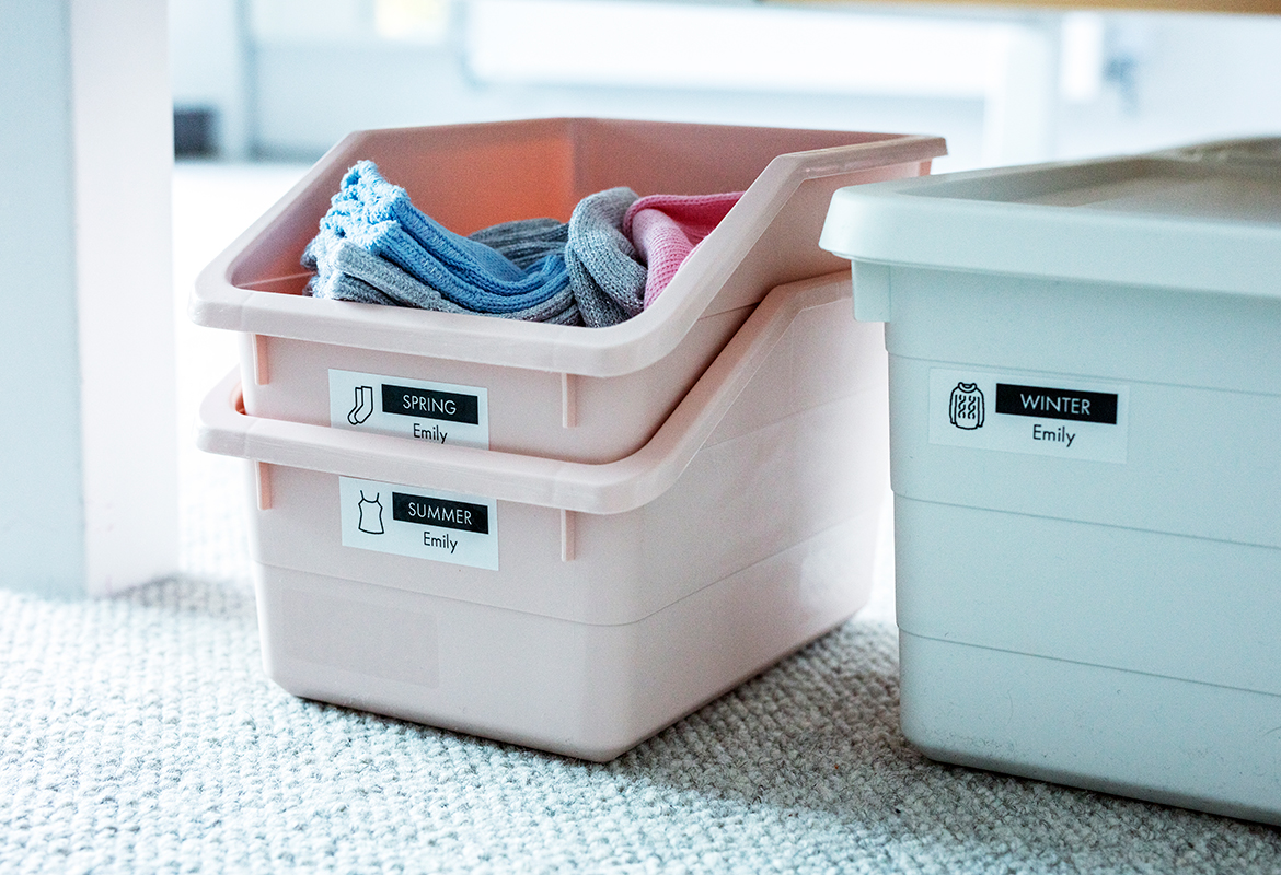  Plastikbehälter mit Socken darin, die mit Etiketten mit Texten und Symbolen versehen sind 