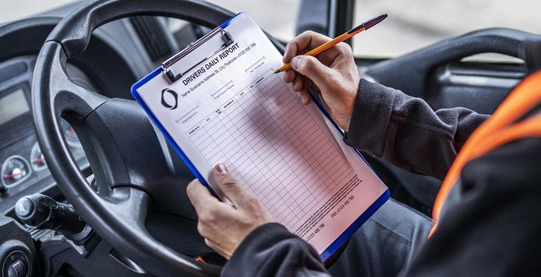 LKW-Fahrer füllt auf Fahrerplatz ein Dokument auf einem Klemmbrett aus