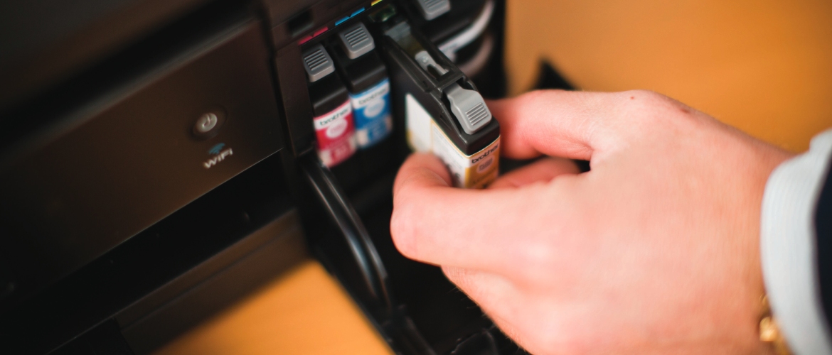Eine Hand, die aus einem Drucker eine Druckerpatrone herauszieht.