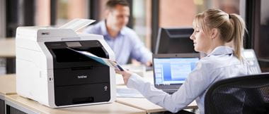 Mujer rubia en oficina recogiendo documento de impresora