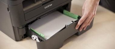 Persona rellenando papel en bandeja de impresora Brother