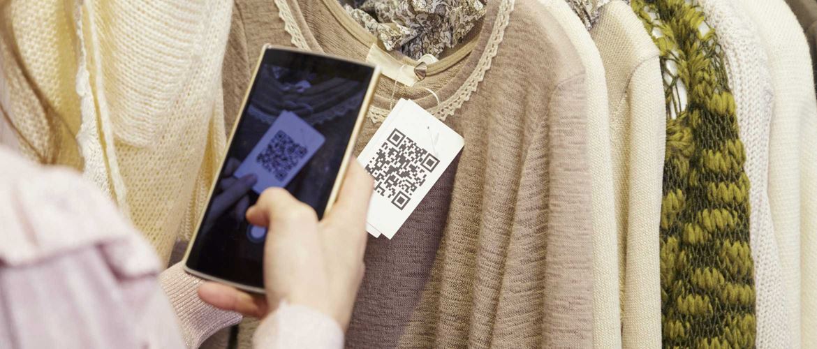 Persona leyendo codigo QR de etiqueta de ropa a través de móvil