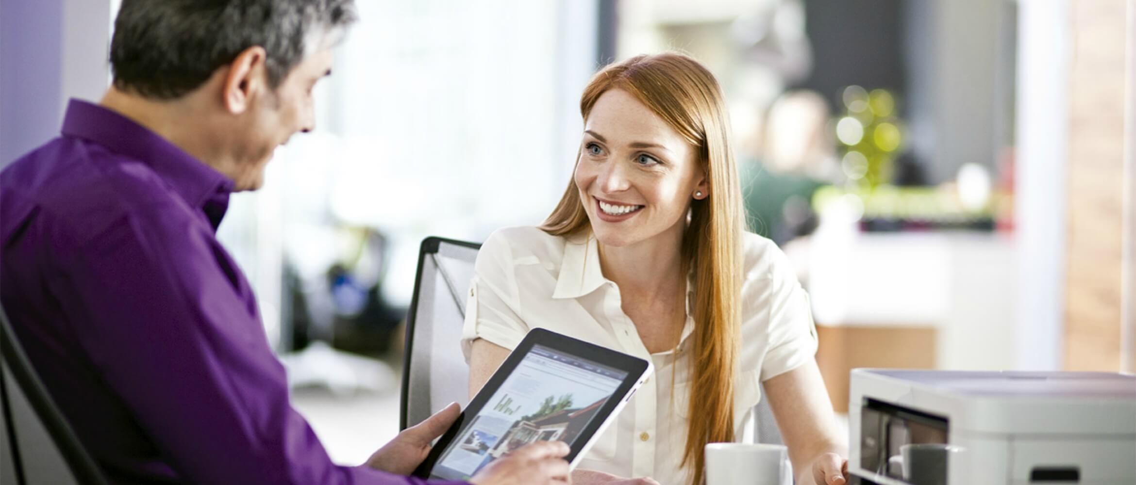 Hombre con tablet y mujer rubia hablando