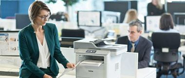 Gente trabajando en oficina y mujer con traje verde sujetando un folio impreso
