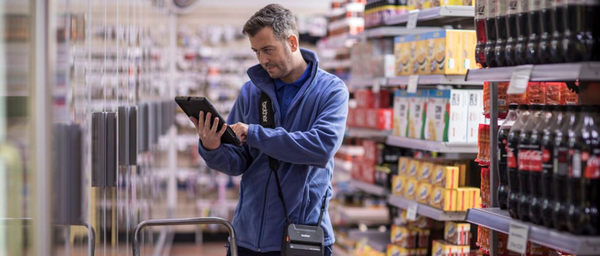 Hombre con tablet e impresora portátil RJ-4 en supermercado