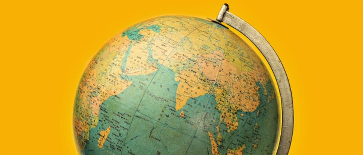 A model globe with a map of the world in front of an orange background