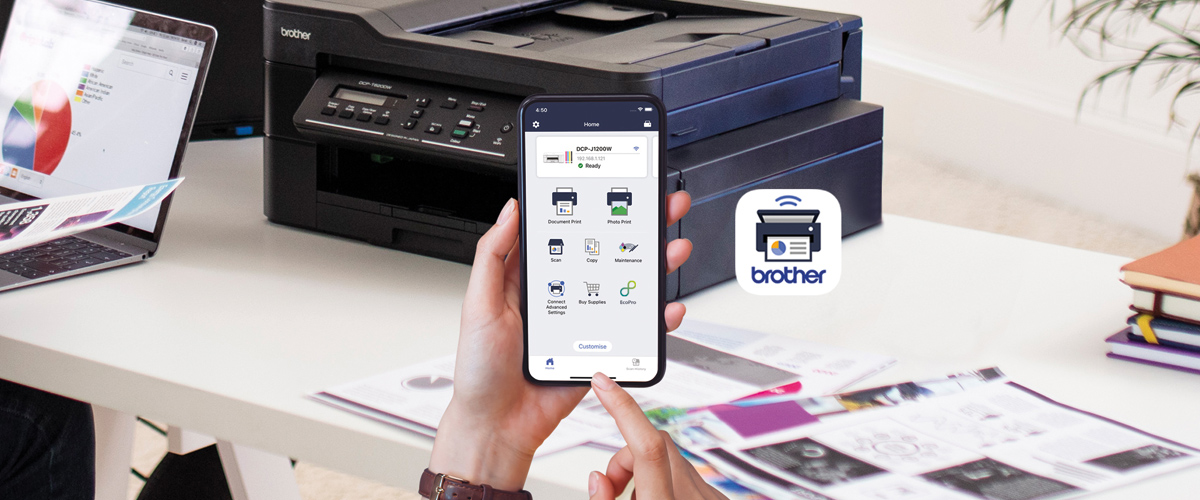 En Brother mobil applikasjon vises på en mobiltelefon, mot bakgrunnen av en svart Brother-skriver på et skrivebord.
