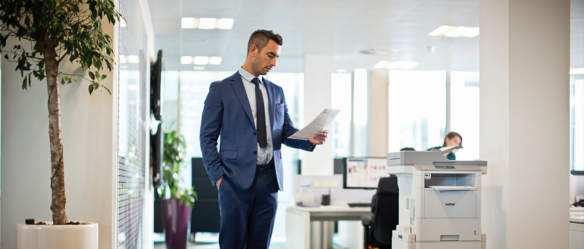 mono laser comes of age man stood by printer reading paper in office