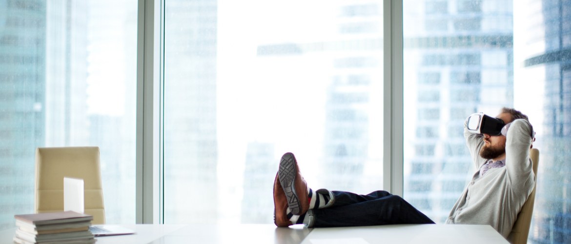 Office of the future - the technological backbone image with a man relaxing while using his VR augmented virtual reality headset for business