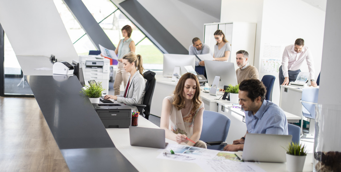 modern office with workers at laptops and having meetings