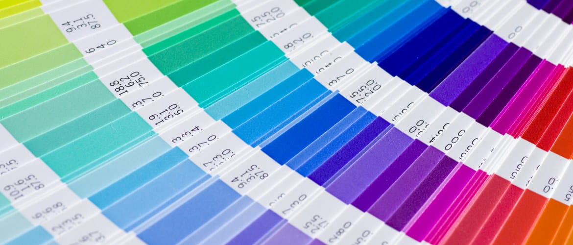 A selection of pantone colours is fanned out in a colour swatch formula guide chart