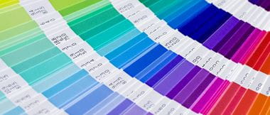 A selection of pantone colours is fanned out in a colour swatch formula guide chart