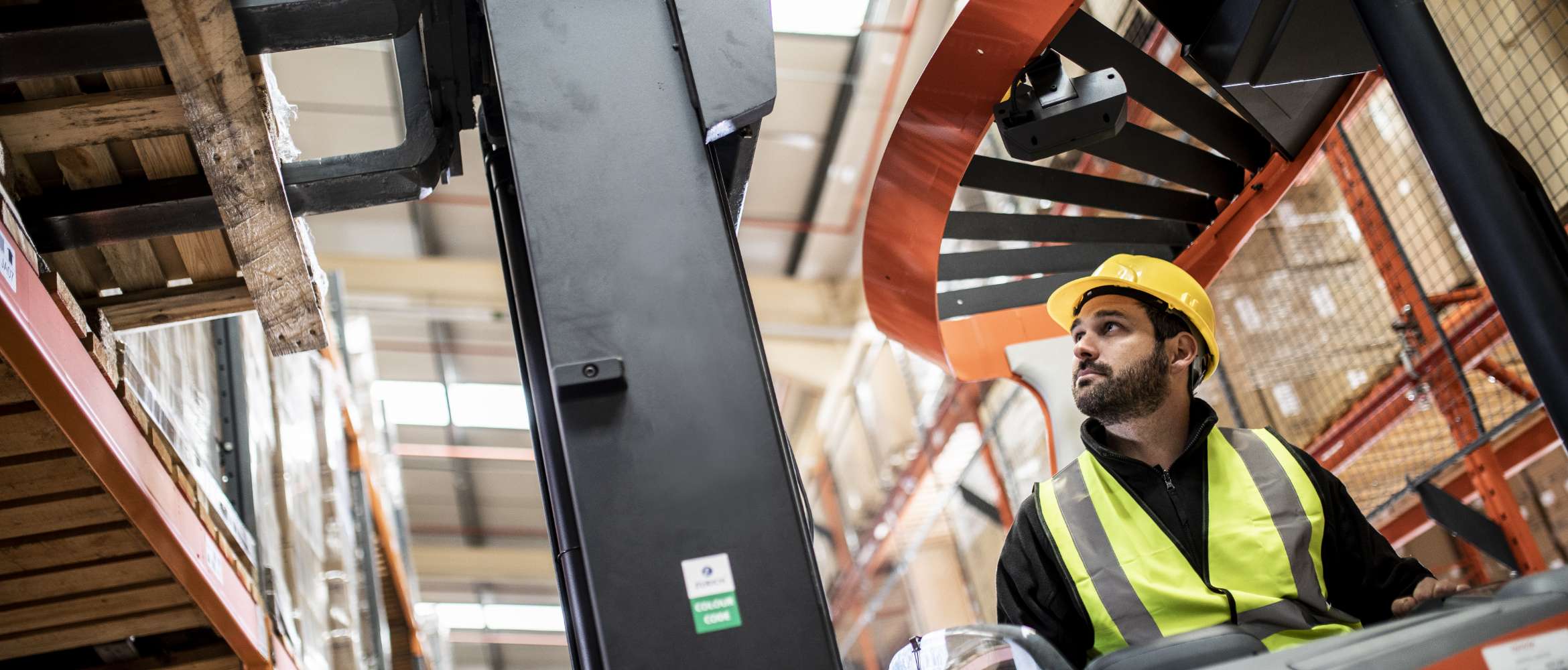 En mannlig fabrikkarbeider kjører en gaffeltruck på et lager