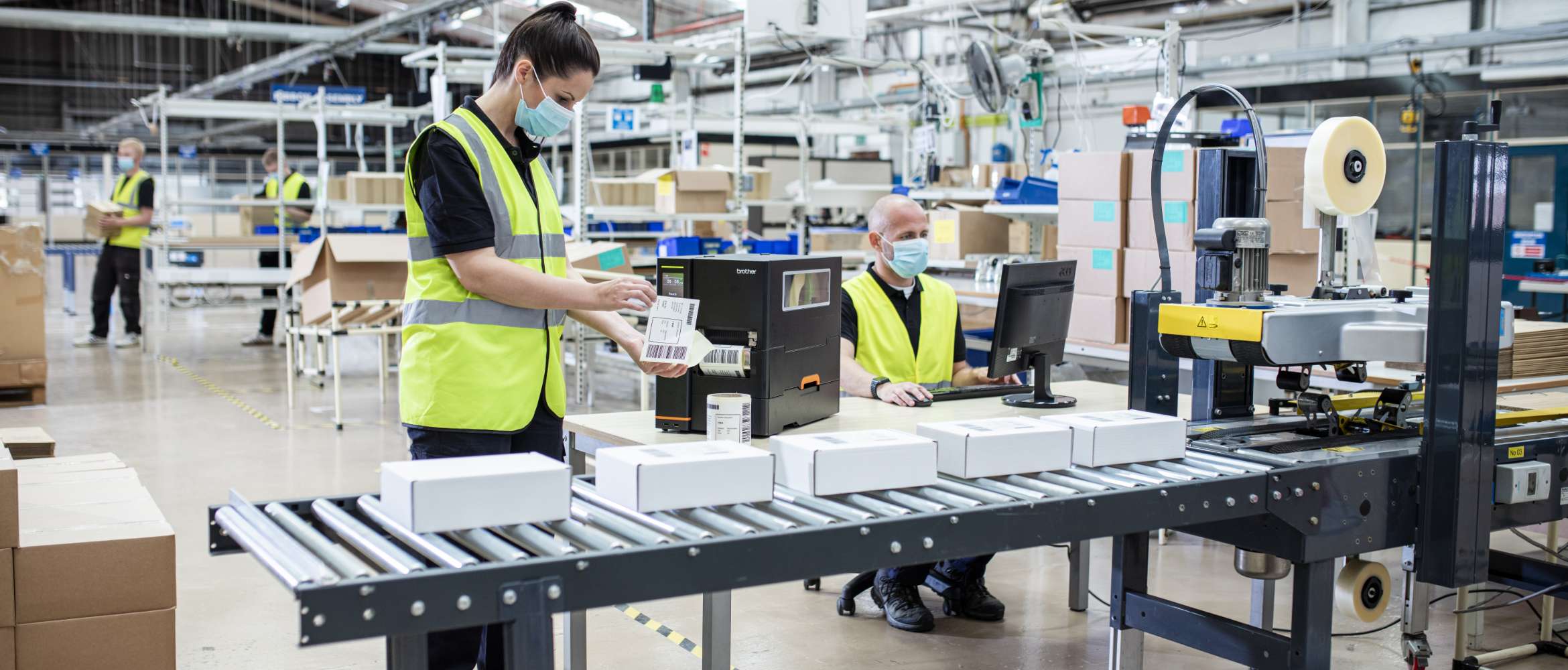 A worker on a factory line in a distributed manufacturing and logistics operation is applying a printed barcode label to a package. 