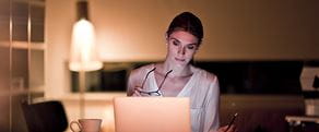 En kvinne sitter hjemme og søker på en datamaskin