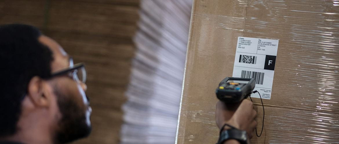 Man scanning shipping label on wrapped box