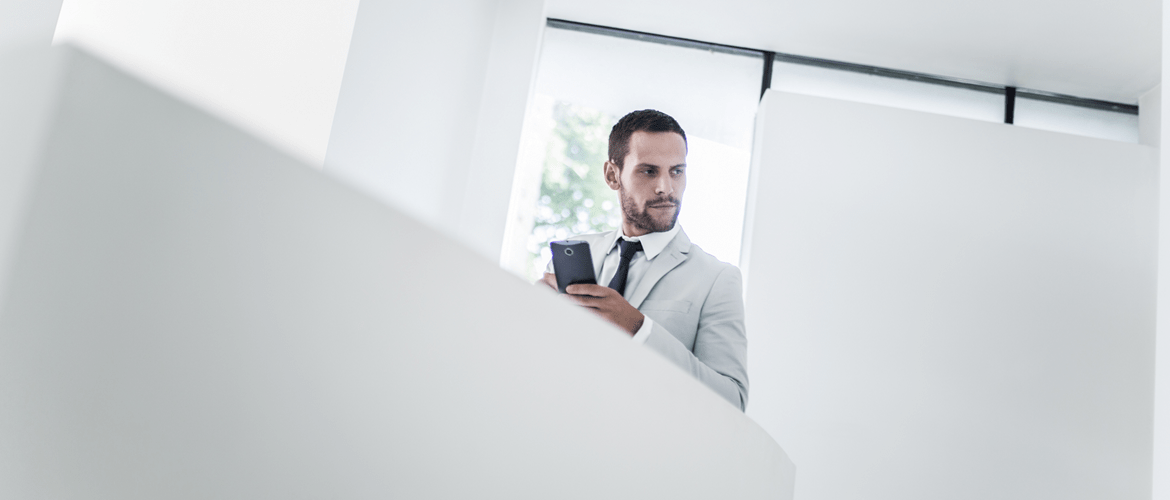 Man in a white suit with Android smartphone overlooking balcony