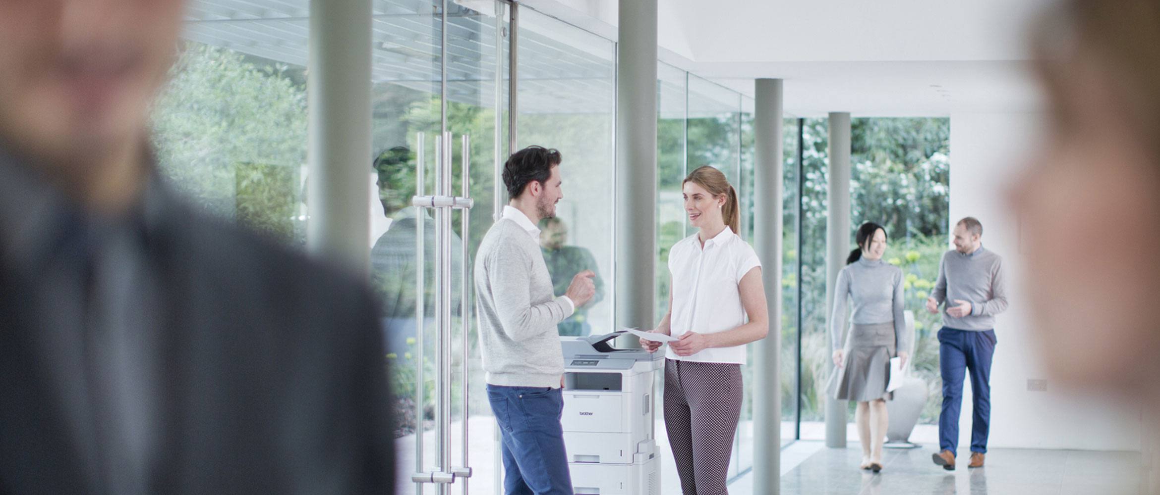 Two colleagues chat at the office printer