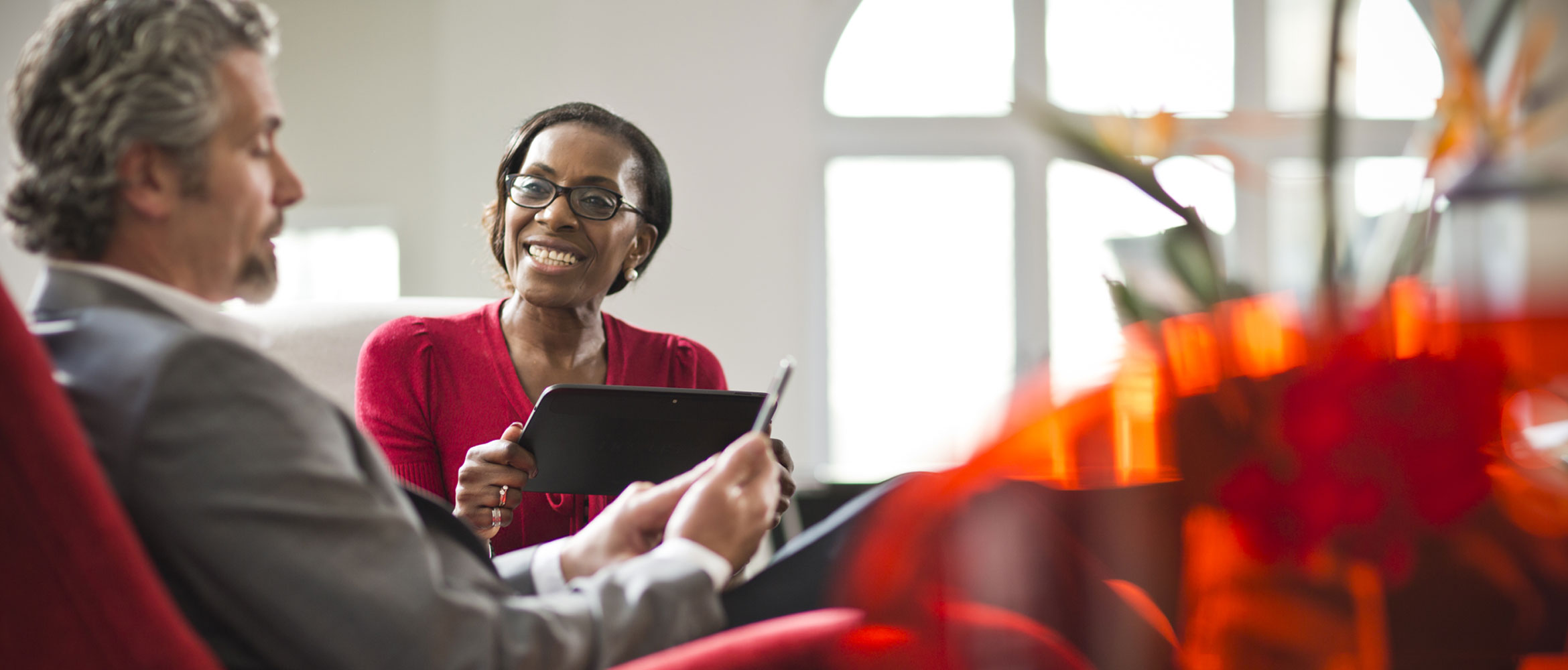 A man and woman holding tablets, talking and smiling