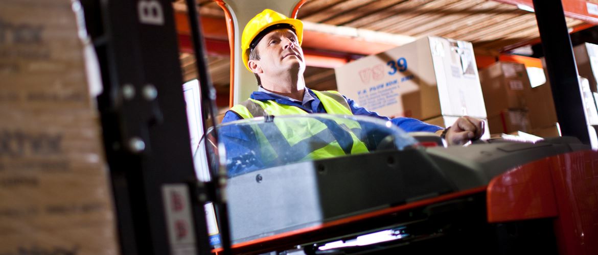Workman operates a crane in a warehouse