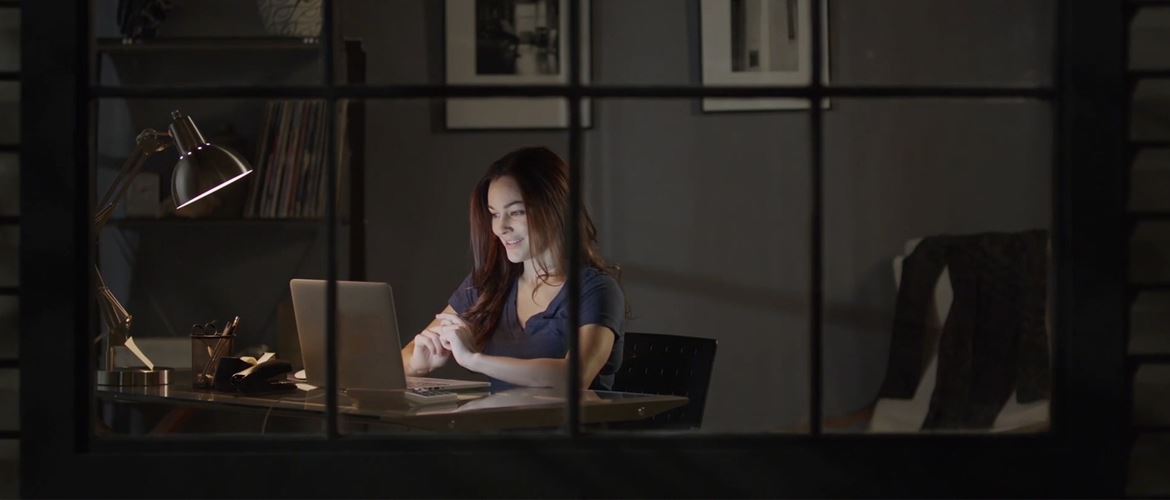 Kobieta siedziąca wieczorem przy biurku z laptopem  