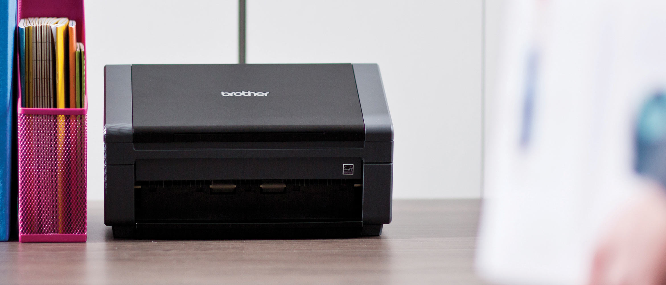 Black Brother document scanner on a desk next to pink file holder