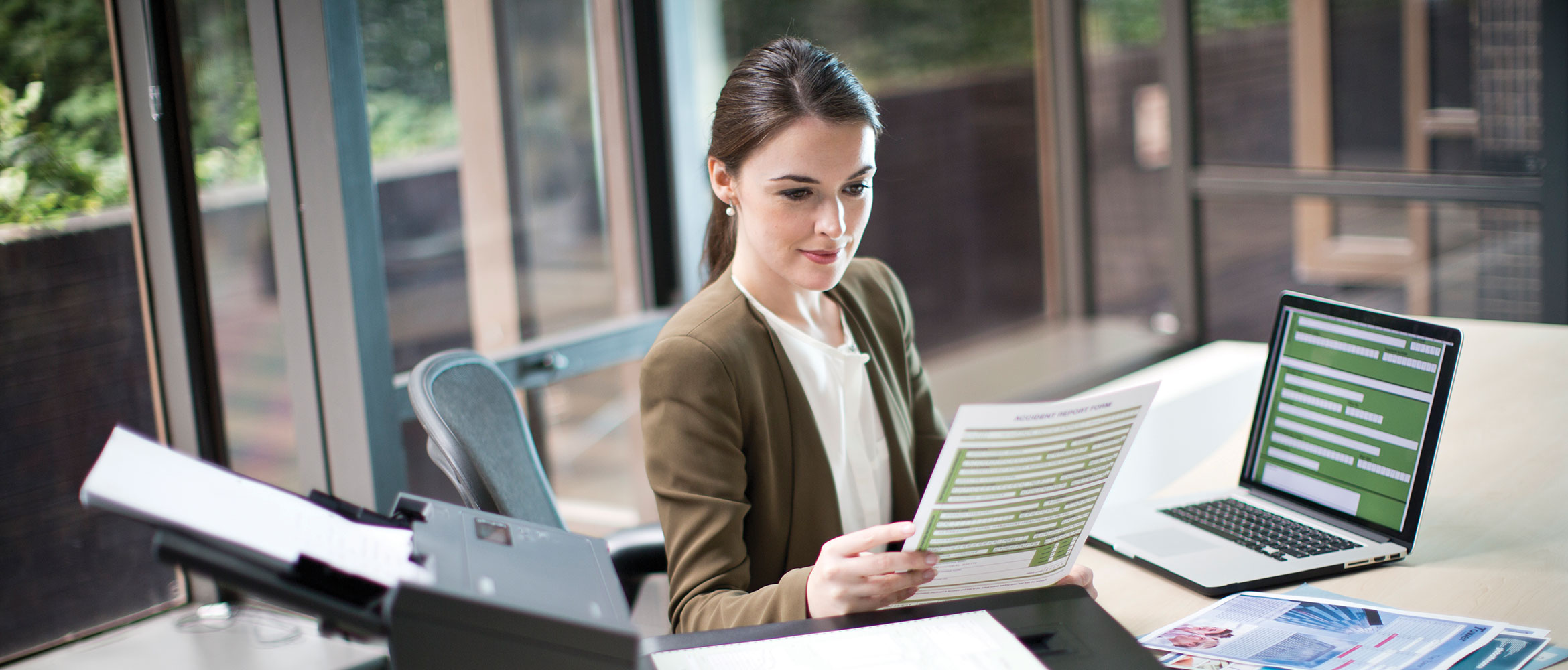 Smiling lady sat at a desk using a Brother document scanner
