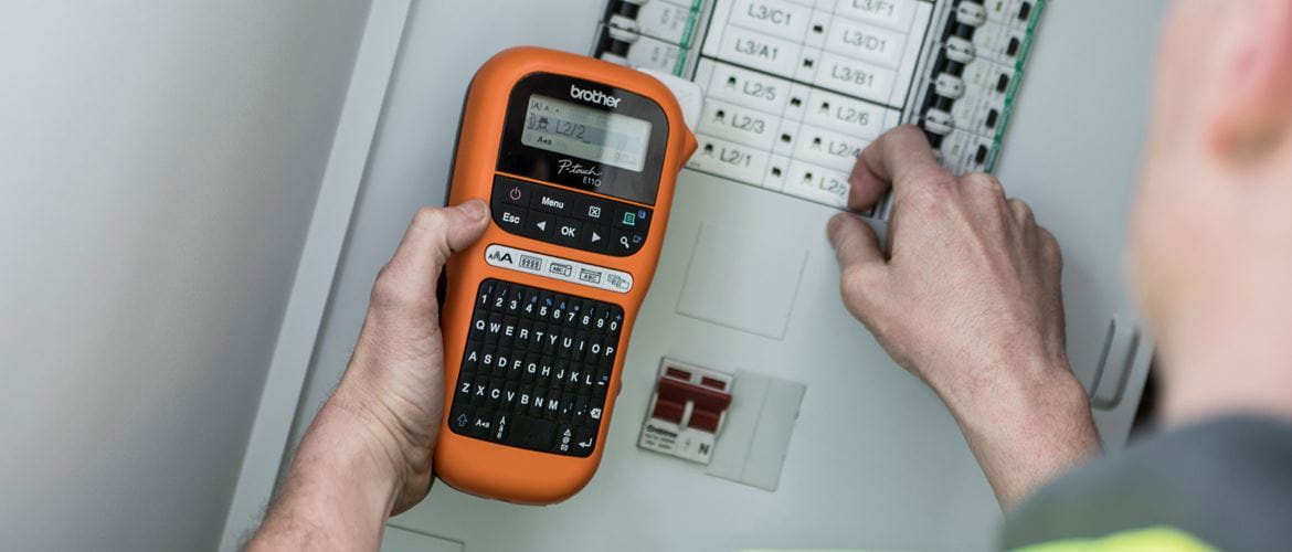 Electrician holding a mobile label printer next to fuse box