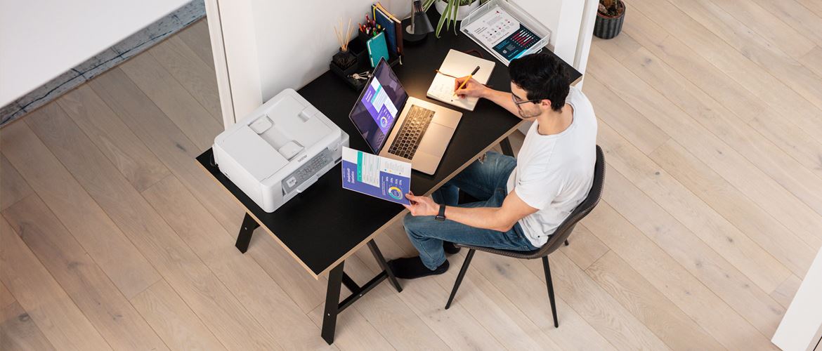 Mand ved skrivebord med laptop og printer