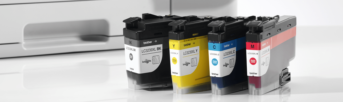 Ink cartridges in black, yellow, cyan and magenta, all lined up next to a printer