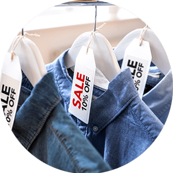 Red and black sale labels on hangers holding denim shirts