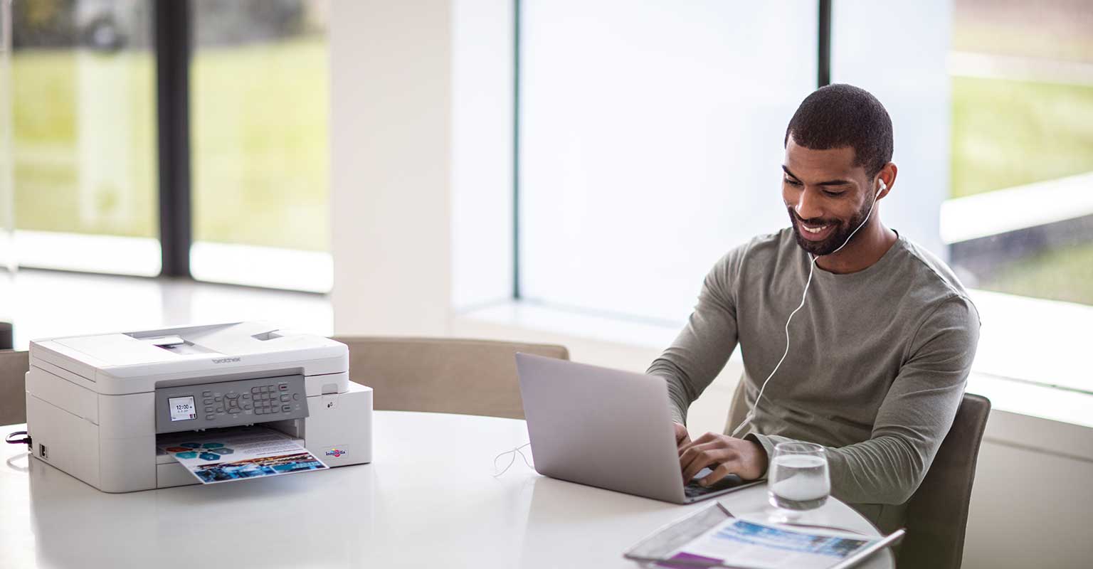 A man working sat next to a Brother wifi printer