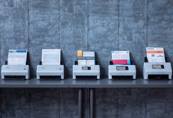 Line-up of desktop scanners with documents on grey table