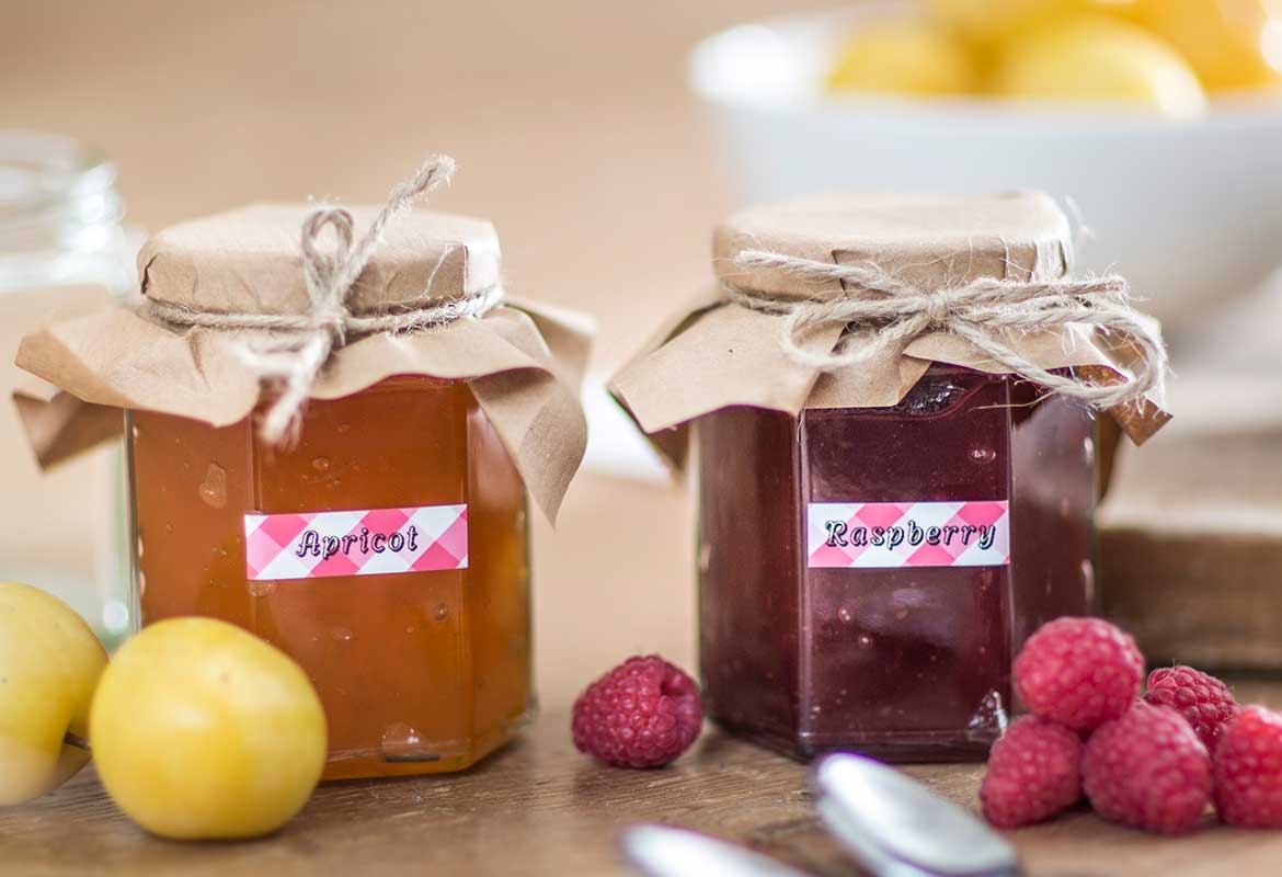 Black on red gingham patterned labels identifying contents of home made jam in jars